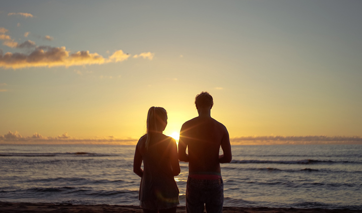casal no pôr do sol de frente para o mar