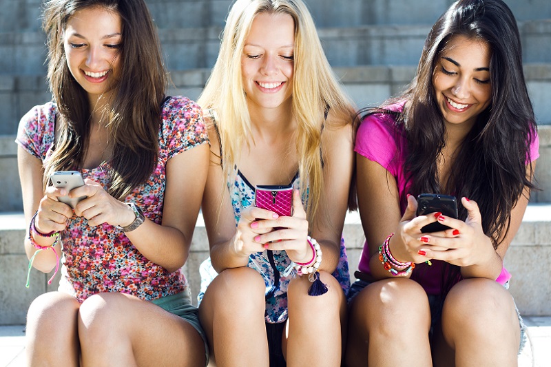 Meninas, sentadas, felizes, sorrindo, mexendo no celular