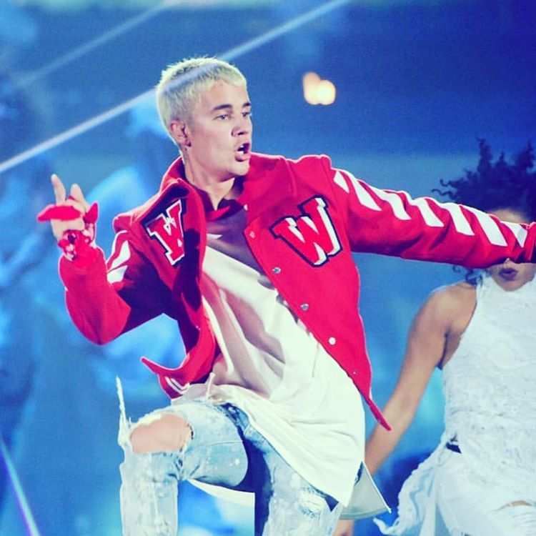 Justin Bieber dançando em seu show com uma blusa vermelha