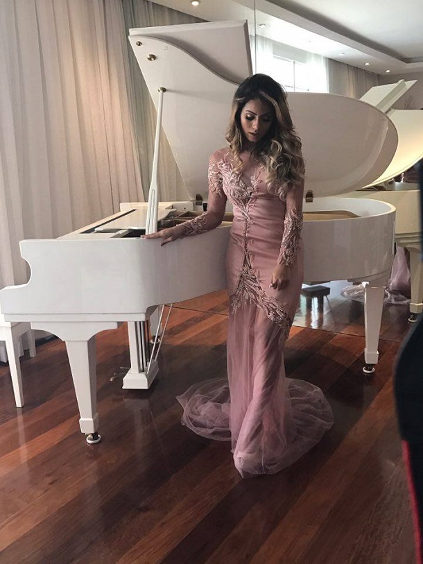 Cantora Lexa, de vestido longo, no piano