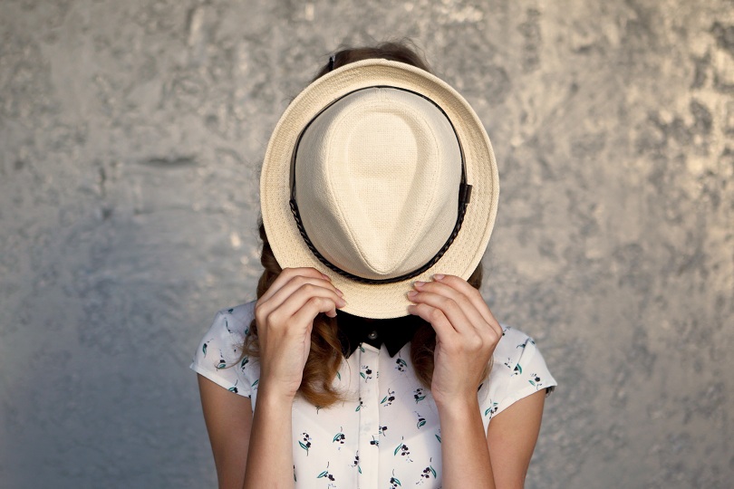 Garota de escondendo atrás de um chapéu branco