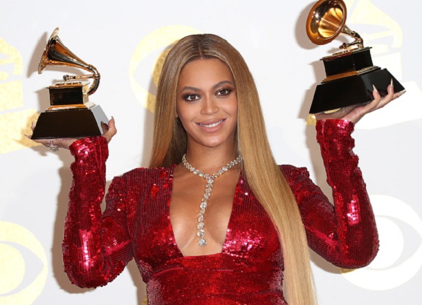 Beyoncé no Grammy com vestido vermelho segurando dois prêmios 