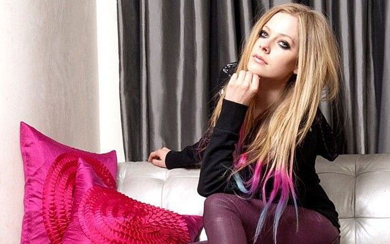 Avril Lavigne sentada ao lado de almofadas rosa