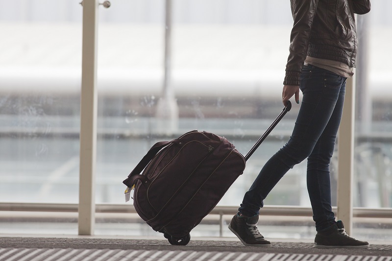 Menina arrastando mala de rodinhas por um aeroporto