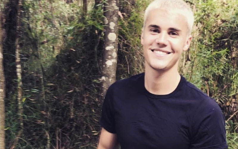 Justin Bieber sorrindo na floresta