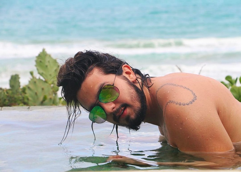 Luan Santana de óculos de sol em uma piscina de borda infinita