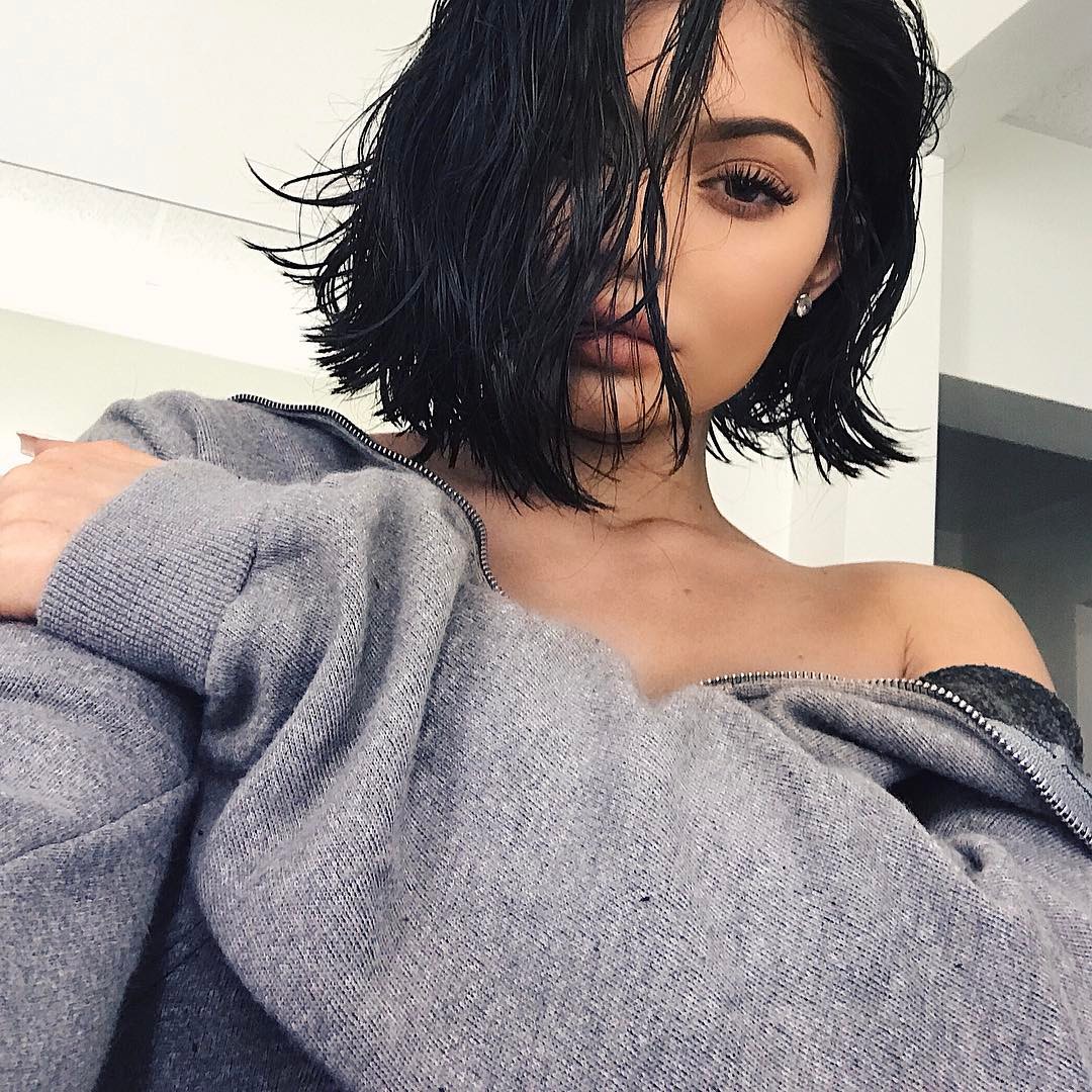 Kylie Jenner com o cabelo curto e castanho, vestindo blusa cinza