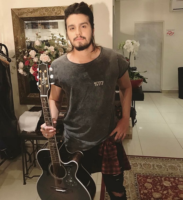 Luan Santana em pé segurando um violão