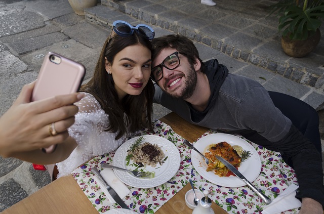 Isis Valverde e Gil Coelho tirando selfie na mesa com comida