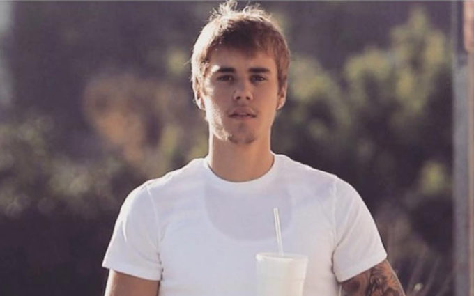 Justin Bieber ao ar livre segurando copo com canudo e usando camiseta branca