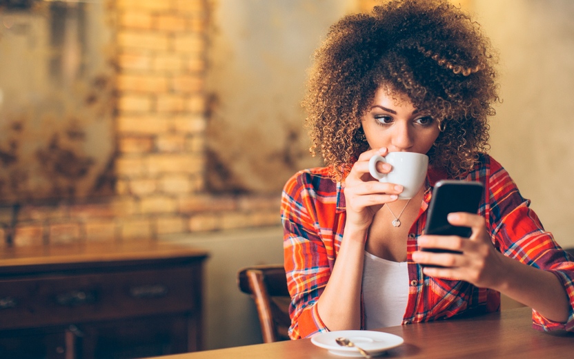 mulher tomando café e mexendo no celular
