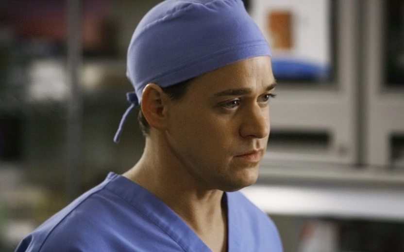 George usando roupa e touca azul de uniforme médico