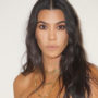 Kourtney Kardashian com os cabelos longos soltos olhando para a câmera