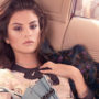 Selena Gomez deitada em banco de caro usando roupas em tons pastéis