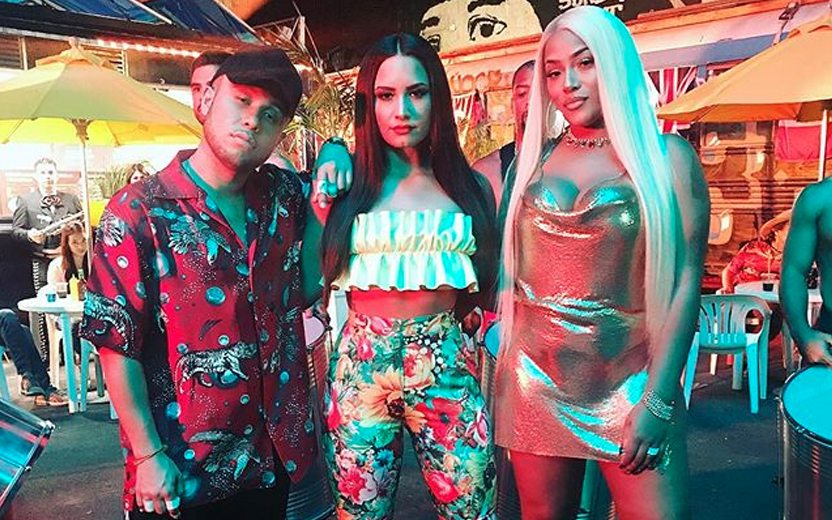 Demi Lovato ao lado do DJ Jax Jones e a rapper Stefflon Don com roupas latinas, estampadas e coloridas