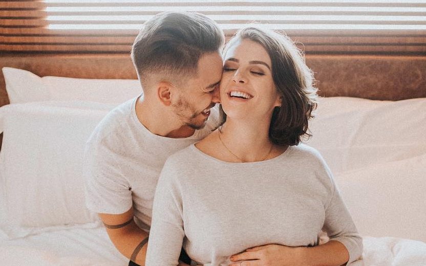 Junior Lima e esposa grávida abraçados sorrindo
