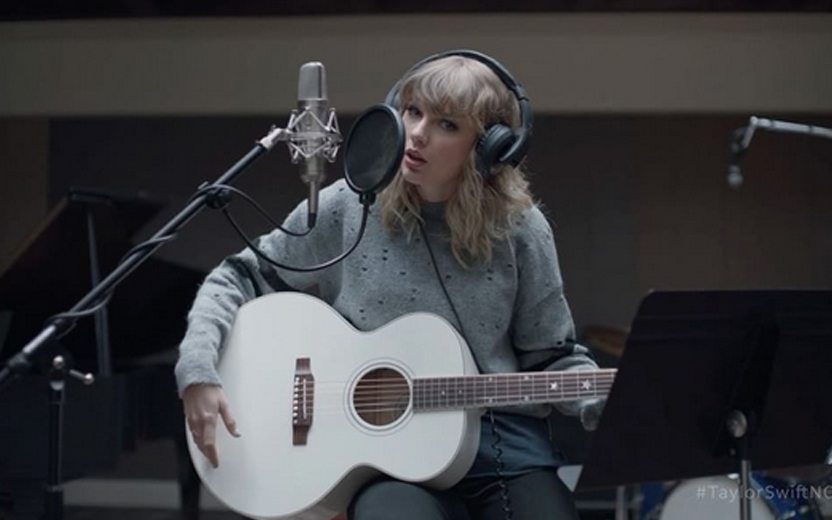 Taylor Swift cantando e tocando violão
