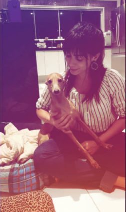 Anitta segurando cachorro e usando franja