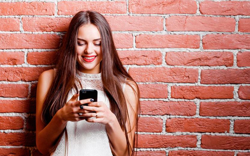 Menina sorrindo enquanto usa aplicativos no celular