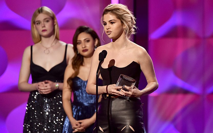Selena Gomez com prêmio de "mulher do ano" na mão