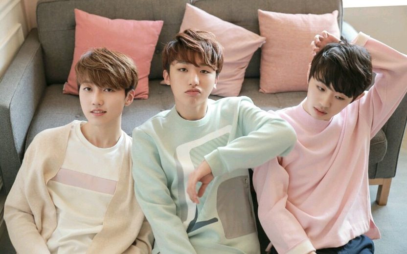 Meninos do grupo MONT sentados em frente a um sofá com almofadas